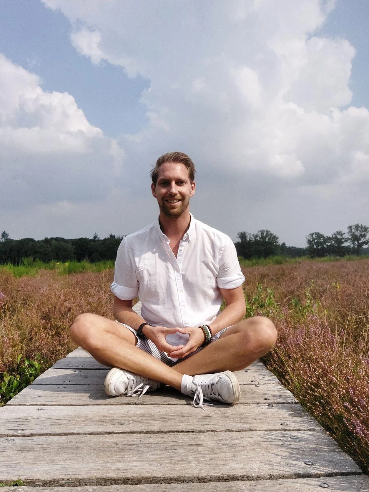 Pieter Oggel zittend in stilte in een heideveld – beeld van mindfulness, balans en innerlijke rust.